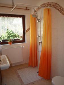an orange shower curtain in a bathroom with a window at Villa Gast - Salmagundi, für Gruppen bis 16 Gäste in Kamp-Bornhofen