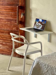 a laptop computer sitting on a table next to a chair at Casa Ingapura Suite Tainha - Povoado Bar da Hora 15 min de canoa para Atins - Estilo B&B - Café da Manhã Simples - Conforto in Atins