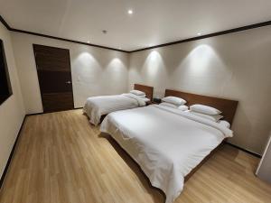 a bedroom with two beds with white sheets at Lounge Seoul in Icheon