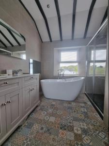 La grande salle de bains est pourvue d'une grande baignoire et d'un lavabo. dans l'établissement Luxurious Cottage with hot tub, Lake District, à Duddon