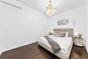 Habitación blanca con cama y lámpara de araña. en Cozy House near Darling Harbor, en Sídney