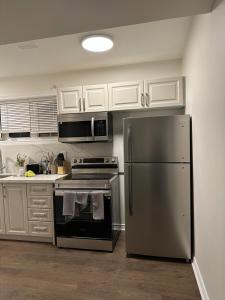 a kitchen with a stainless steel refrigerator and white cabinets at 4 Guests, 2 bedrooms, 2 queen beds basement apartment in Ajax in Ajax