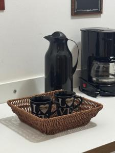 a basket with three cups on a counter with a coffee maker at Flats Linda Vista Para o Mar in Macaé