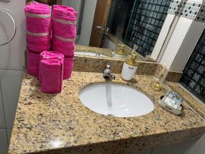 a bathroom counter with a sink and pink towels at Flats Linda Vista Para o Mar in Macaé +21 photos