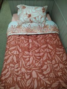 a bed with a red and white comforter and pillows at Habitacion Canelo in Castro