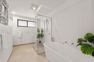 a white bathroom with a tub and a shower at Gorgeous 4 Bedroom House - Blackmans Bay in Kingston Beach +54 photos