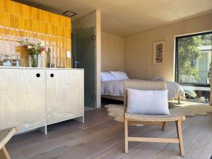 a bedroom with a bed and a chair and a cabinet at Waiheke Horizons Palm Beach in Waiheke Island