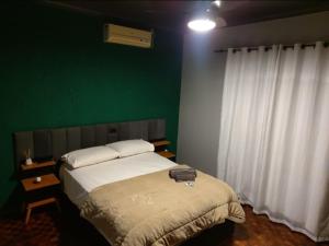 a bedroom with a bed and a green wall at Recanto Arvoredo casa 3 quartos piscina garagem e NF para 12 hospedes in Concordia +28 photos