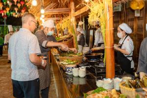 un gruppo di persone in piedi in una cucina che preparano il cibo di Katie Homestay a Phu Quoc