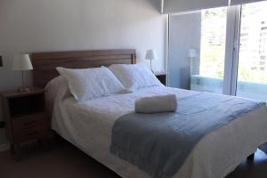 a bedroom with a large bed with white sheets and pillows at Hermoso Departamento 7 en Concepción con Terraza y Estacionamiento in Concepción +20 photos