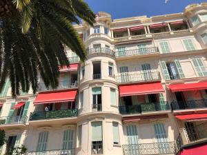 un grand bâtiment blanc avec des auvents rouges dessus dans l'établissement Appartement 4 pers à Menton, 60 m² - FR-1-196-378, à Menton