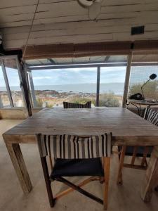a wooden table with a chair and a large window at Casa camarones in Camarones