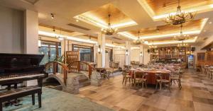 a restaurant with a piano and tables and chairs at 莫干山缦田生态度假酒店 in Deqing