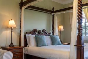 a bedroom with a canopy bed with blue pillows at 6B Luxury Rustic Farm Manor In Lang Lang in Lang Lang