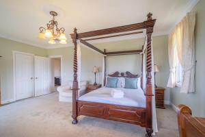 a bedroom with a four poster bed with blue pillows at 6B Luxury Rustic Farm Manor In Lang Lang in Lang Lang