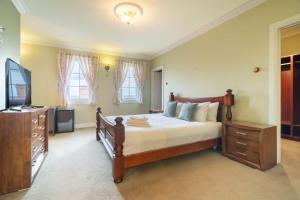 a bedroom with a large bed and a television at 6B Luxury Rustic Farm Manor In Lang Lang in Lang Lang