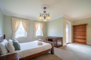a bedroom with a bed and a desk and windows at 6B Luxury Rustic Farm Manor In Lang Lang in Lang Lang