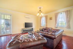a living room with leather furniture and a flat screen tv at 6B Luxury Rustic Farm Manor In Lang Lang in Lang Lang