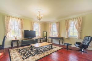 a living room with a tv and a table and chairs at 6B Luxury Rustic Farm Manor In Lang Lang in Lang Lang