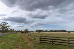 a fence on the side of a road next to a field at 6B Luxury Rustic Farm Manor In Lang Lang in Lang Lang