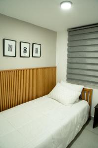 a bed in a bedroom with three pictures on the wall at La Haus Paipa beautiful and modern house in Paipa