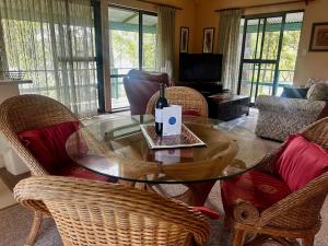 un salon avec une table en verre et des chaises dans l'établissement Fyshwicks Cottage, à Smiths Lake