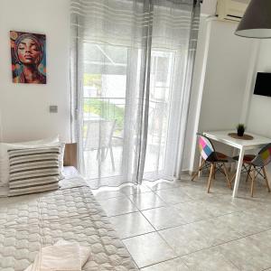 a bedroom with a bed and a table and a window at R&T Apartments in Kallithea Halkidikis