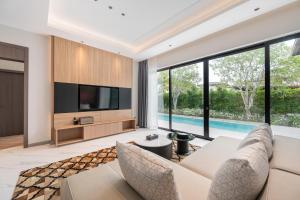a living room with a white couch and a tv at Argo Pattaya Resort and Villas in Ban Huai Yai