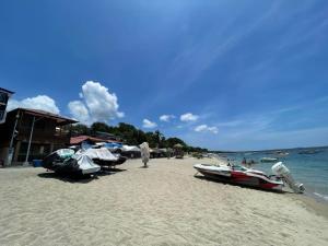 a beach with boats and a man standing on the sand at Casa Dolores Laiya Batangas in San Juan
