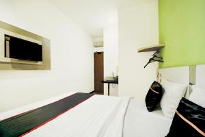 a bedroom with a white bed and a flat screen tv at Hotel O Symphony Homestay Tlogomas in Malang +22 photos