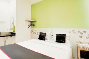 a bedroom with a white bed with black pillows at Hotel O Symphony Homestay Tlogomas in Malang