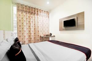 a bedroom with a bed with a tv on the wall at Hotel O Symphony Homestay Tlogomas in Malang
