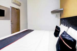 a bedroom with a white bed with a black headboard at Hotel O Symphony Homestay Tlogomas in Malang