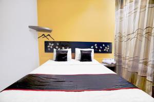 a bedroom with a large bed with black and white pillows at Hotel O Symphony Homestay Tlogomas in Malang