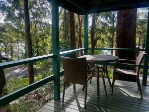 - une terrasse couverte avec une table et des chaises dans l'établissement Fyshwicks Cottage, à Smiths Lake