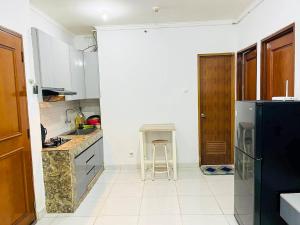 Una cocina con un refrigerador negro y una encimera. en Cozy Room by StayIn Jakarta, en Yakarta