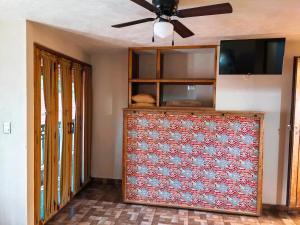 a living room with a ceiling fan and a dresser at Posada Ángel in Cedro