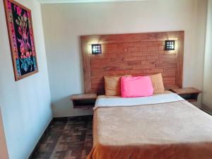 a bedroom with a bed with a pink pillow on it at Posada Ángel in Cedro