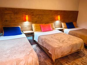 a room with three beds with colorful pillows on them at Posada Ángel in Cedro