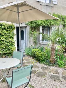 a table and two chairs with an umbrella at Le Layris - Maison indépendante avec cour in Campan