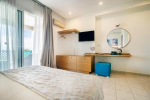 a bedroom with a bed and a mirror at Aegean Sun Hotel in Skala Rachoniou