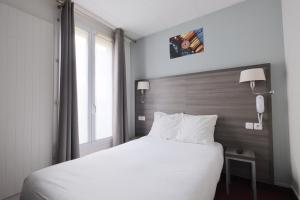 a bedroom with a white bed and a window at Hotel Lilas Gambetta in Paris