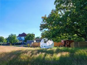 eine weiße Kuppel auf einem Feld mit einem Haus in der Unterkunft Bubble Tent by Reindahls in Wilkendorf