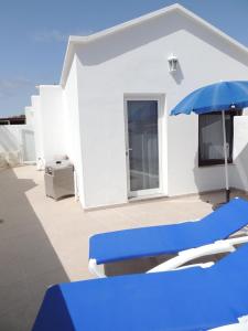 a white house with a blue umbrella and chairs at Apartment Luna FKK Nudist Place in Charco del Palo