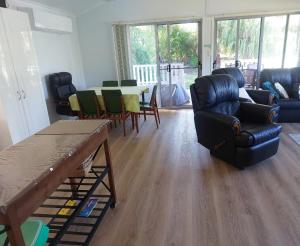 a living room with a couch and a table and chairs at Palm Grove Holiday Home in Agnes Water