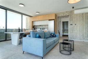 a living room with a blue couch and a kitchen at Avenue 201 2 BED in Paphos