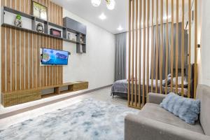 Красотка в сером في أستانا: غرفة معيشة مع أريكة وتلفزيون على الحائط