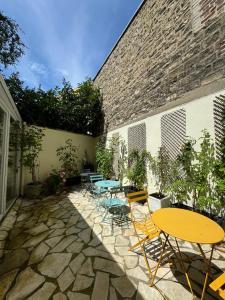 a patio with tables and chairs and a building at Hotel Lilas Gambetta in Paris