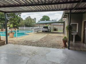 a car parked under a pergola next to a pool at Sibahlenomhlambi Guesthouse in Springs +5 photos