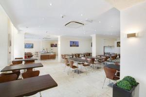 a restaurant with tables and chairs in a room at Queens Park Hotel in London